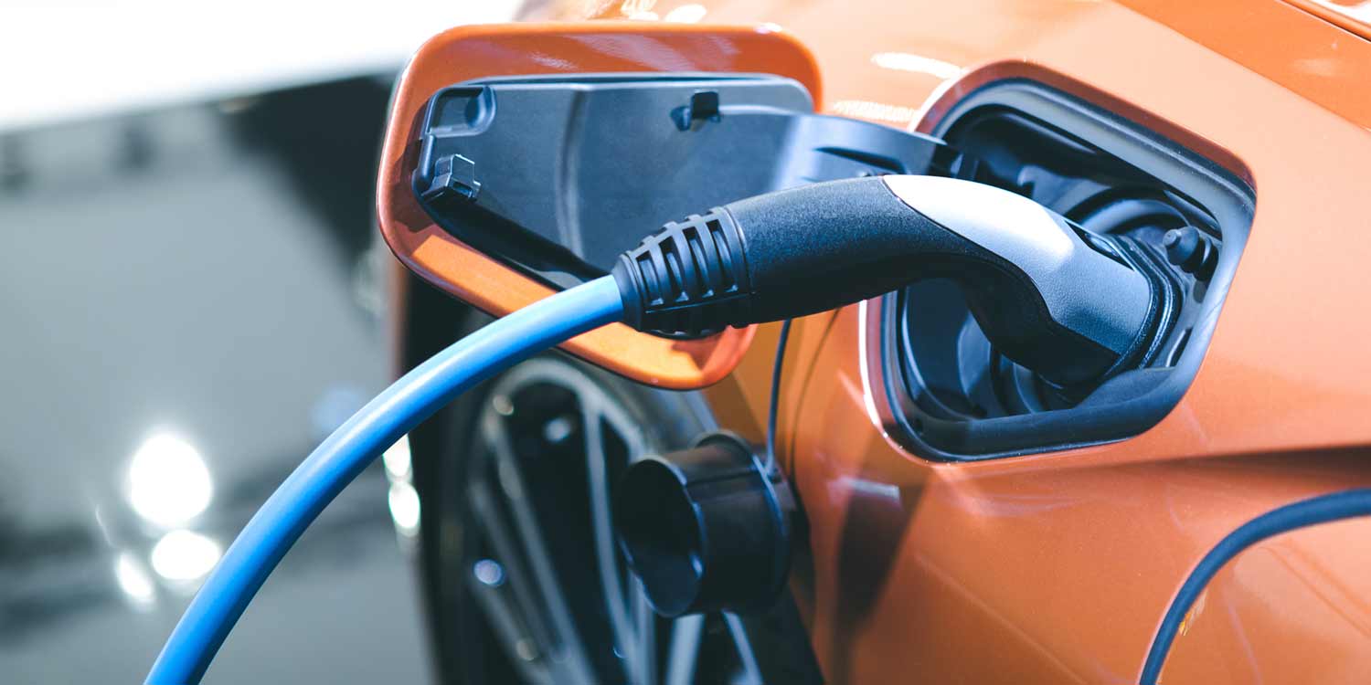 An orange electric vehicle plugged into a charging station.