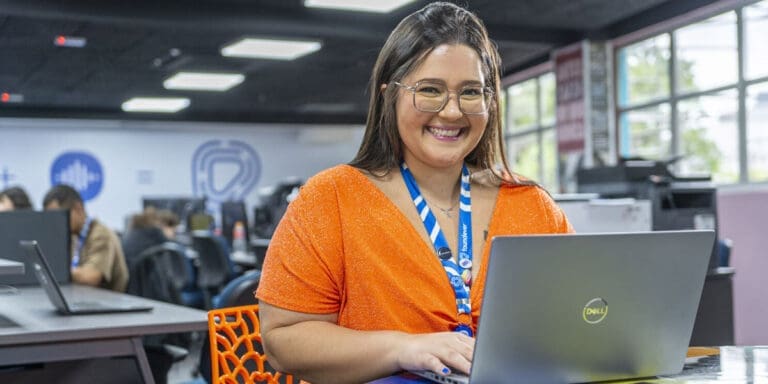 A Foundever customer care agent smiles while working from a laptop