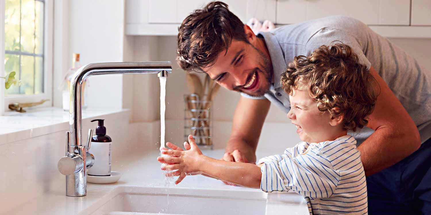 Father with daughter washing hands at a sink