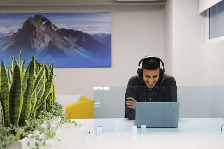 A person is working remotely looking at a laptop and wearing headphones