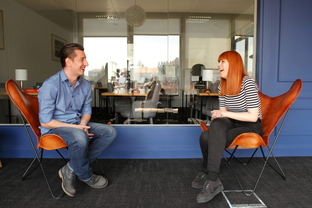 Two Foundever associates sitting in leather chairs and chatting in the office