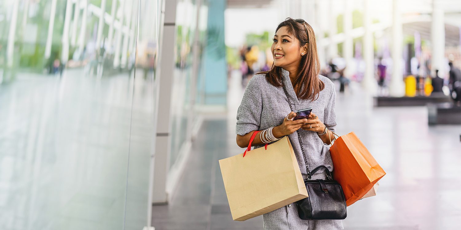 Woman with shopping bags looking in store windows. Customer loyalty.