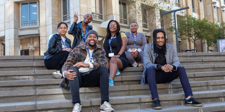 employee experience to drive engagement and success; a group of Foundever employees gather for a photo on the steps in front of a building