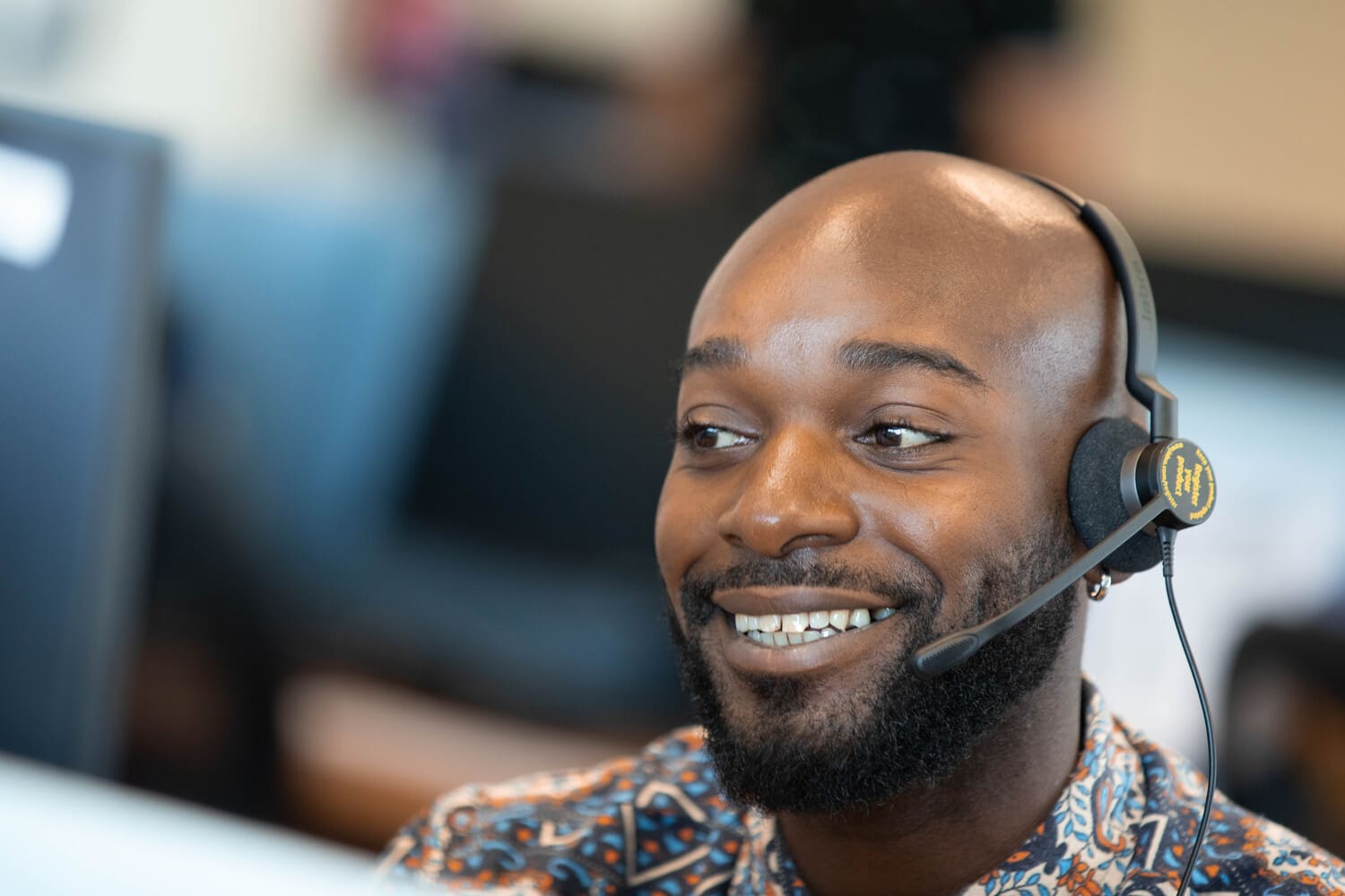 A Foundever associate in Spain is taking calls wearing a headset and smiling