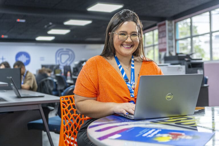 A Foundever customer care agent smiles while working from a laptop