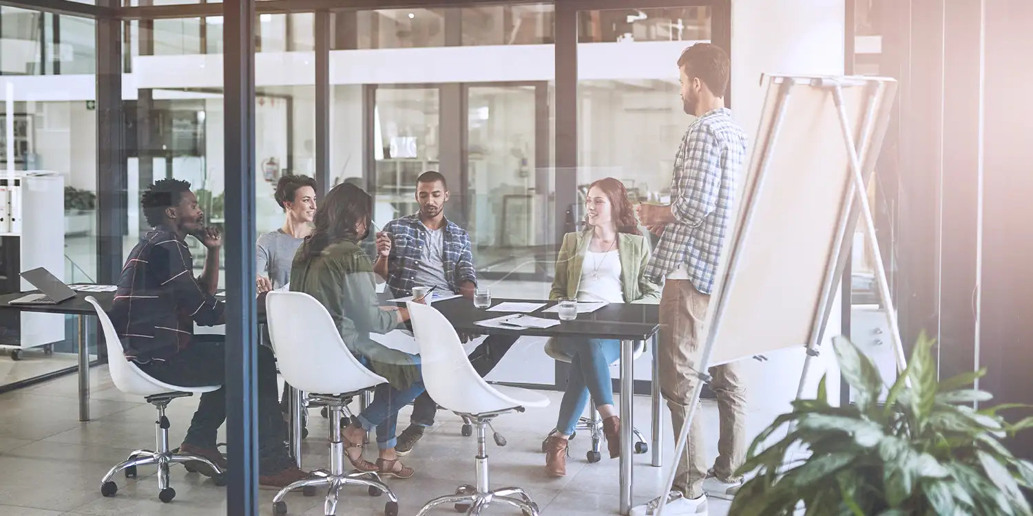 A small group of people are meeting in an office conference room to plan and collaborate
