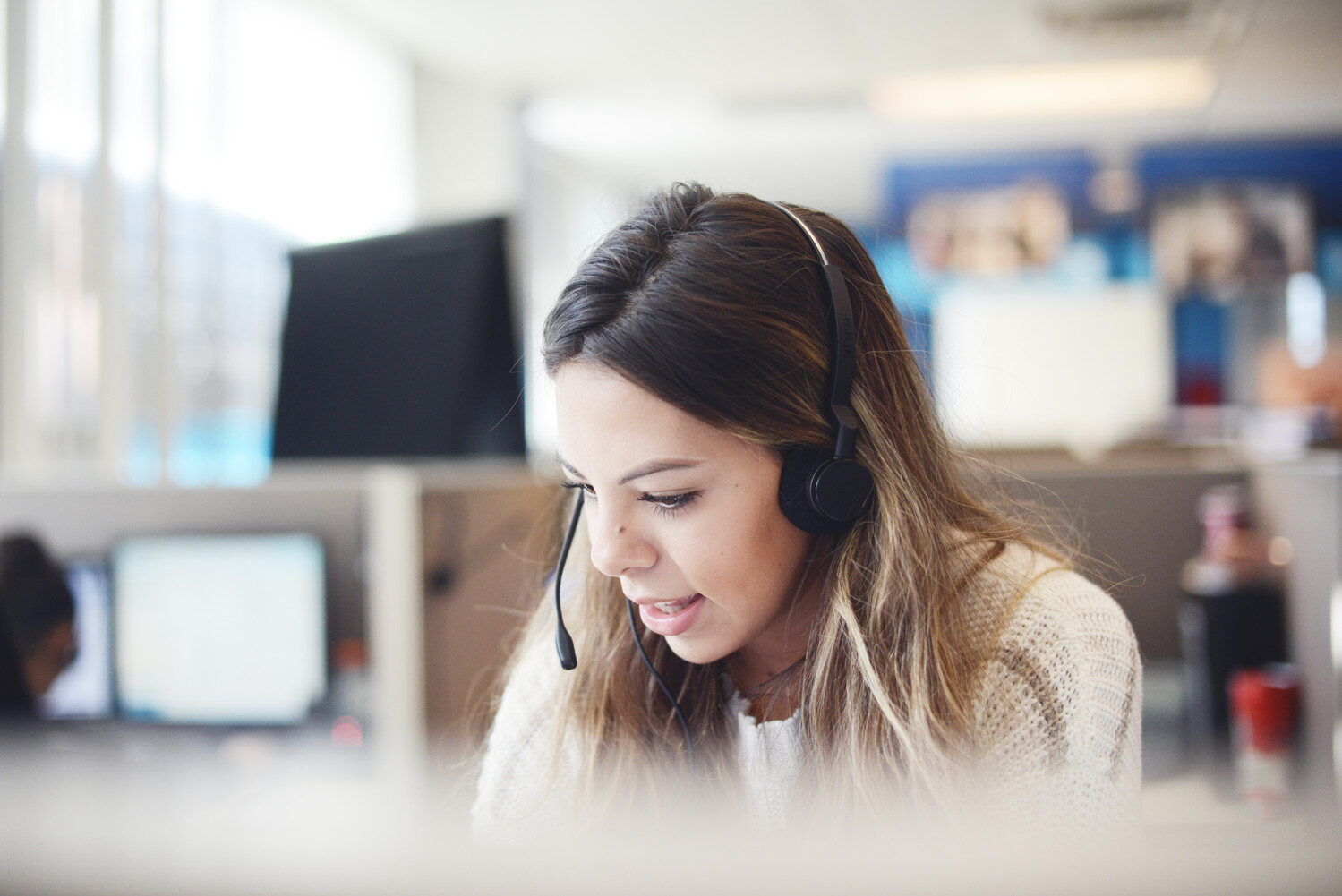 A Foundever associate wearing a headset takes a call from a customer
