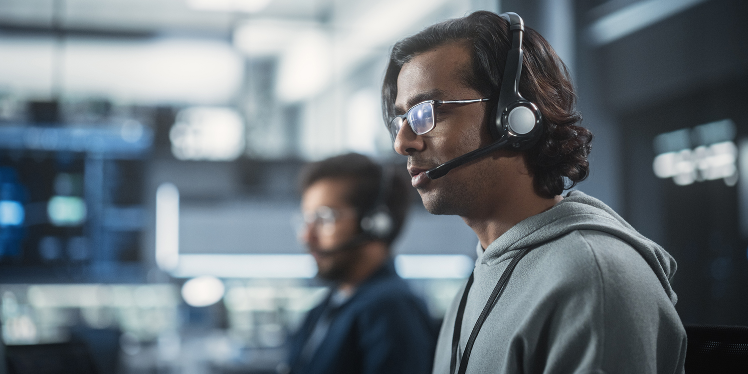 Two male agents wearing headsets are taking customer calls