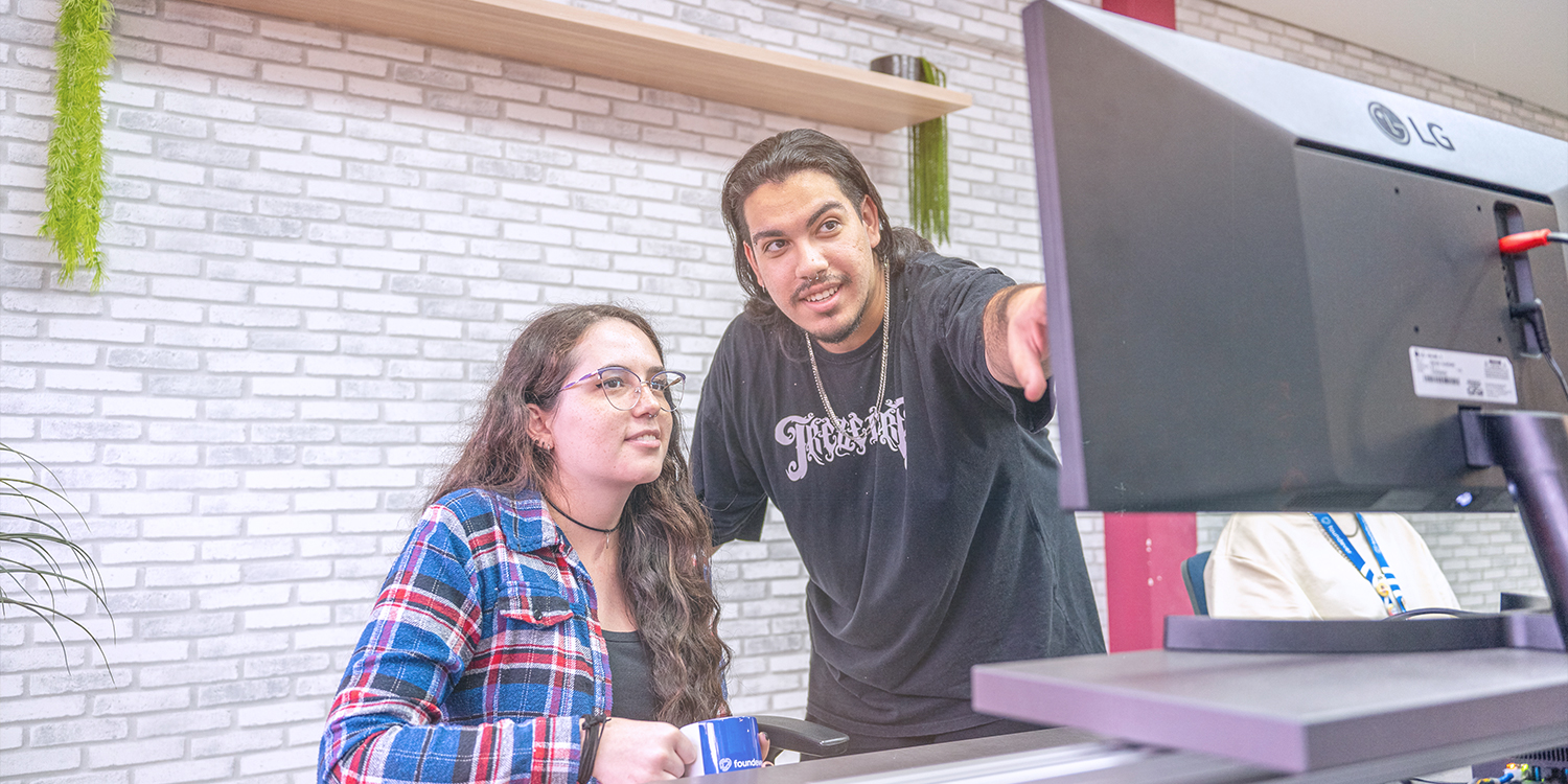 Two Foundever associates discuss customer care for a client while looking at a computer monitor