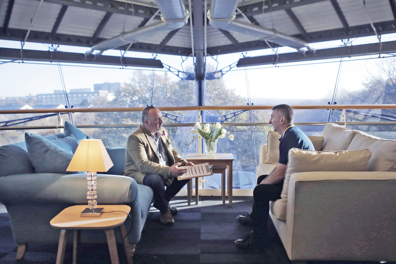 A manager coaches an employee while sitting opposite each other on sofas in an office area