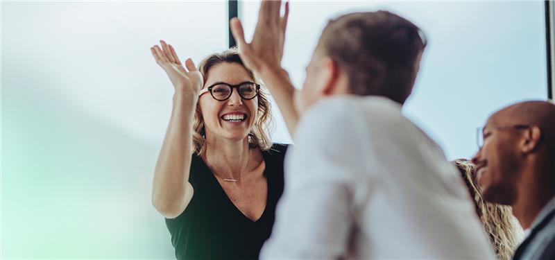 Three employees high-fiving each other