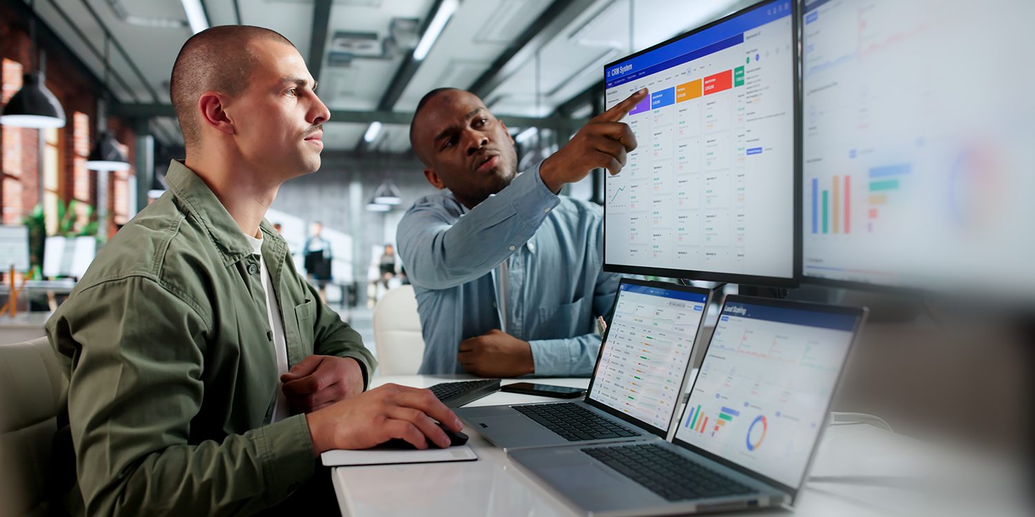 Two men look at computer screens with data displayed
